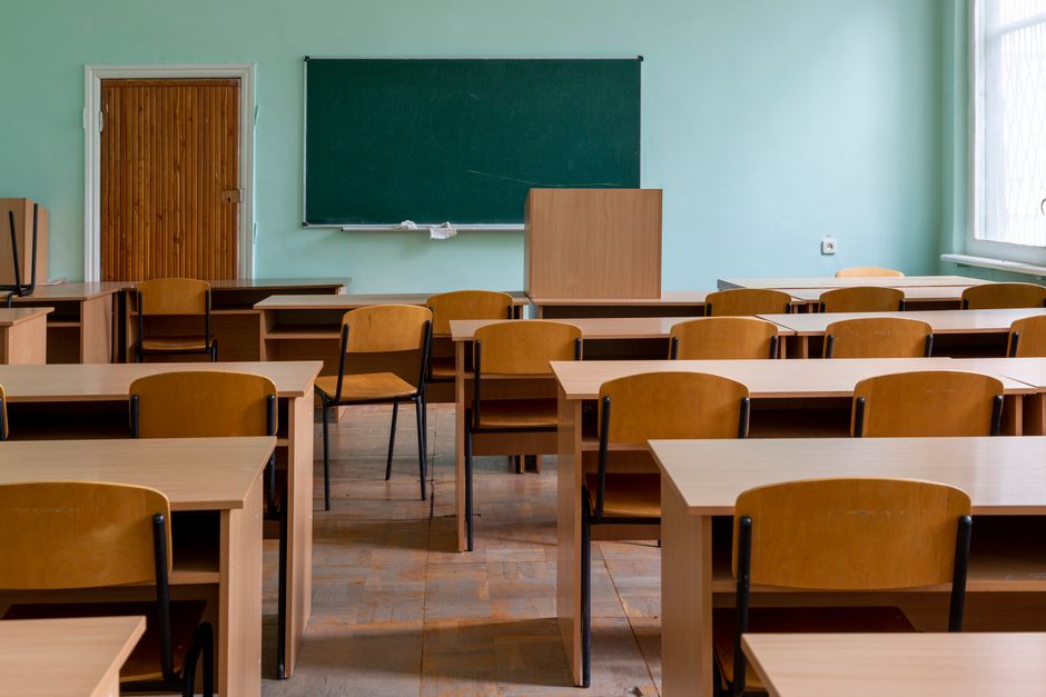 Prazna učionica s drvenim stolovima, stolicama i velikom zelenom pločom