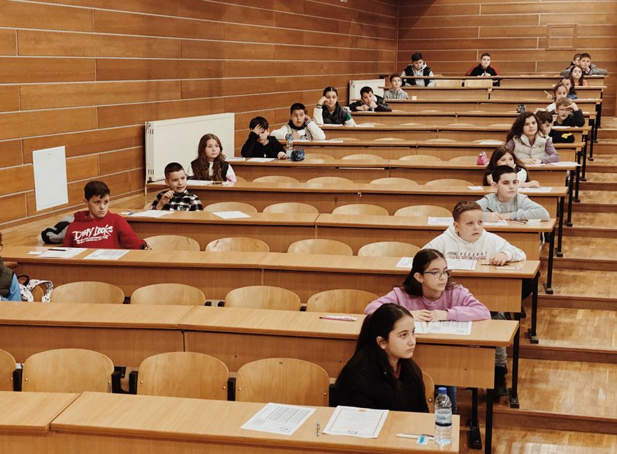 Učenici sjede u redovima u predavaonici, usredotočeni na ispite